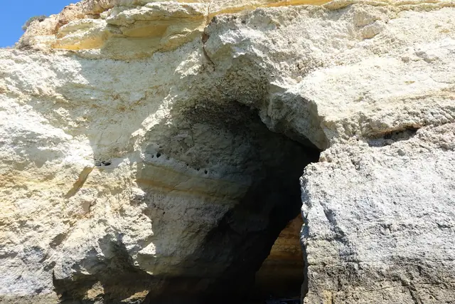 Golden limestone rock and a cave opening on the coast at Benagil in the Algarve