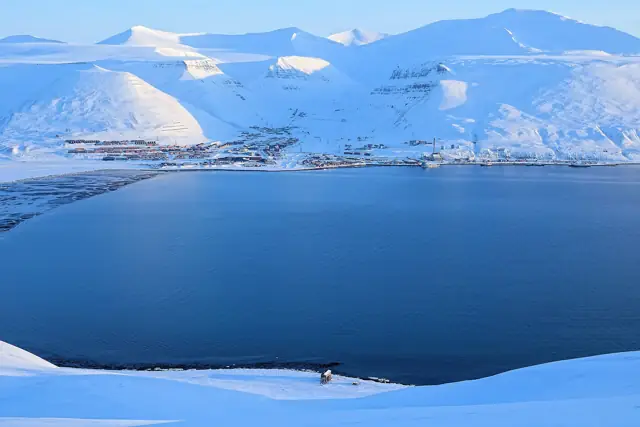 Snow-covered mountains and the frozen fjord around Longyearbyen, seen from above in winter