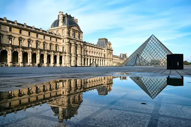 The Louvre's glass pyramid and the Denon wing reflected in a puddle in the Cour Napoléon