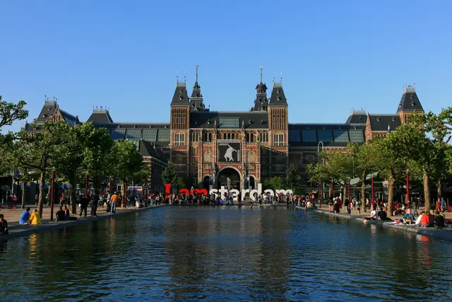 The red-brick Rijksmuseum building seen across the Museumplein reflecting pool