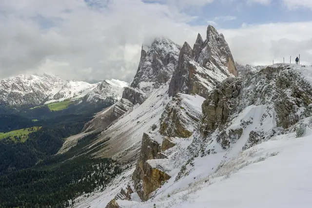 The jagged Odle peaks seen from the Seceda ridge, dusted with snow above a green valley