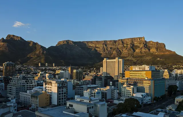 The flat top of Table Mountain glowing at dawn above the high-rise buildings of central Cape Town