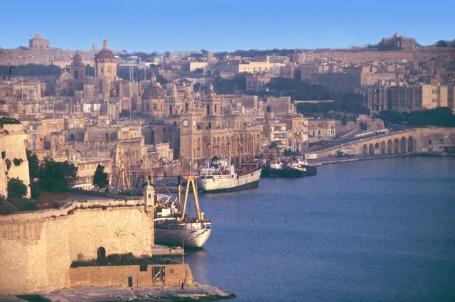 Valletta's honey-coloured buildings and fortifications above the Grand Harbour, with boats moored below