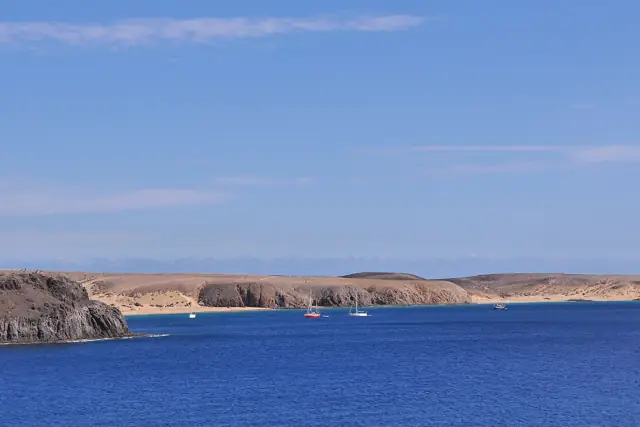 Turquoise sea and golden cliffs at the Papagayo beaches on the southern tip of Lanzarote under a clear blue sky