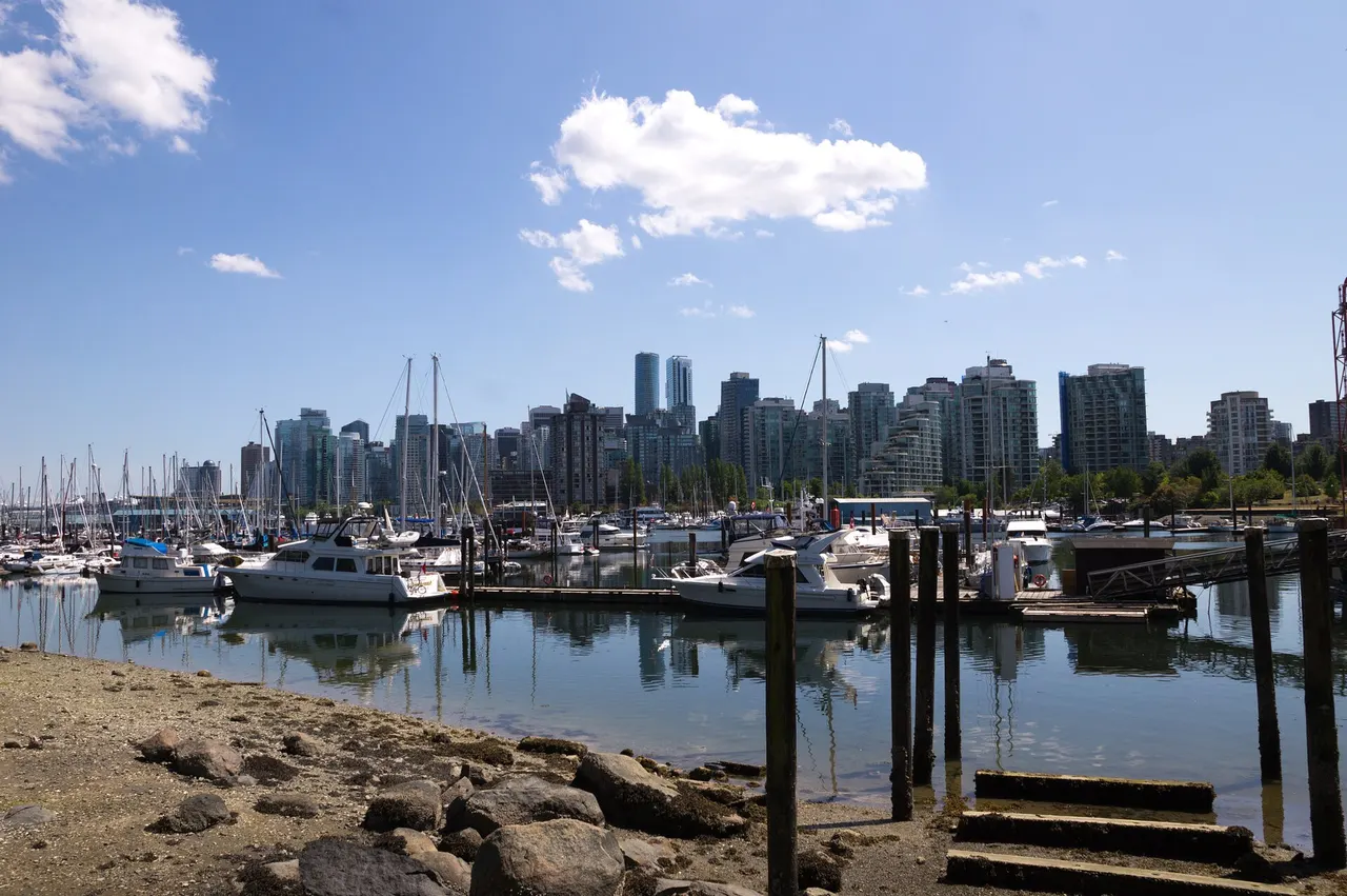 Downtown Vancouver towers behind the boats of a marina at Coal Harbour on a sunny day