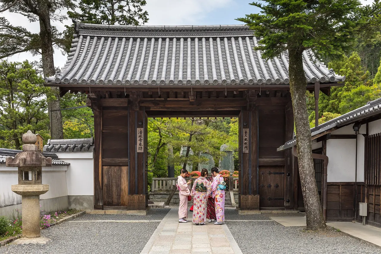 Women in summer yukata in front of the vermilion North Gate of Kiyomizu-dera temple in Kyoto
