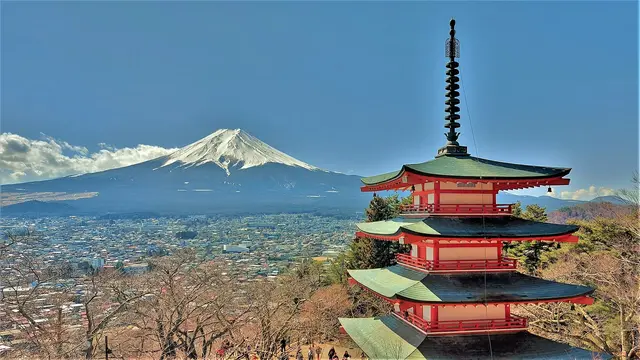 The red five-storey Chureito Pagoda on a wooded hillside with snow-capped Mount Fuji behind it