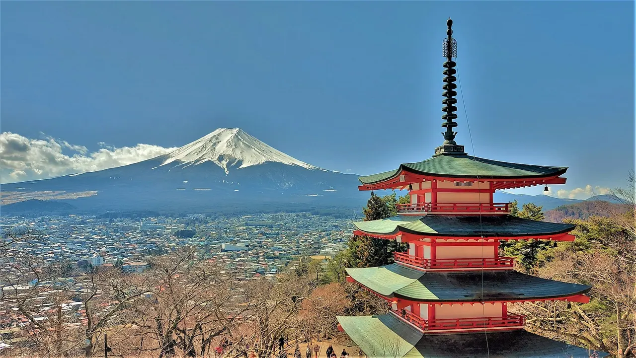 The red five-storey Chureito Pagoda on a wooded hillside with snow-capped Mount Fuji behind it