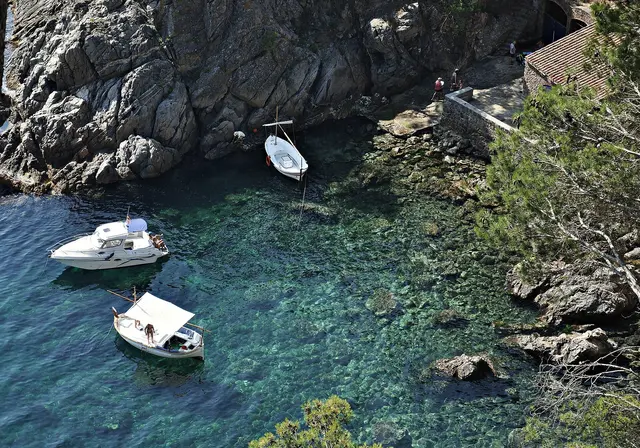 Small boats moored in a clear turquoise rocky cove at Calella de Palafrugell on the Costa Brava