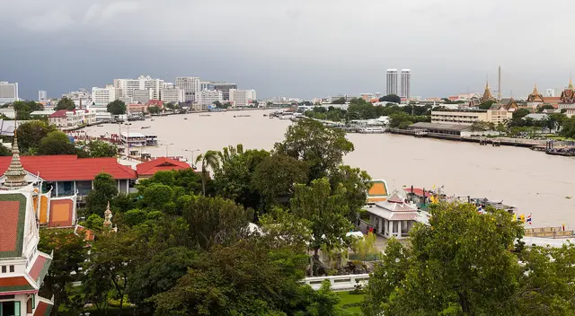 Boats on the Chao Phraya River in Bangkok, with the city skyline along the riverbank