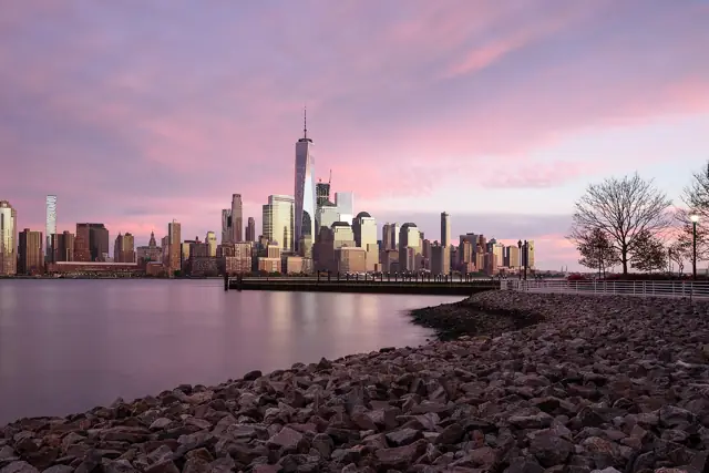 The Lower Manhattan skyline and One World Trade Center at sunset, seen across the Hudson River from Jersey City